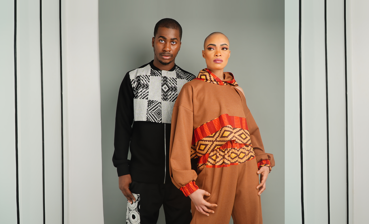 Stylish duo in modern Afrocentric clothing striking a bold pose indoors.