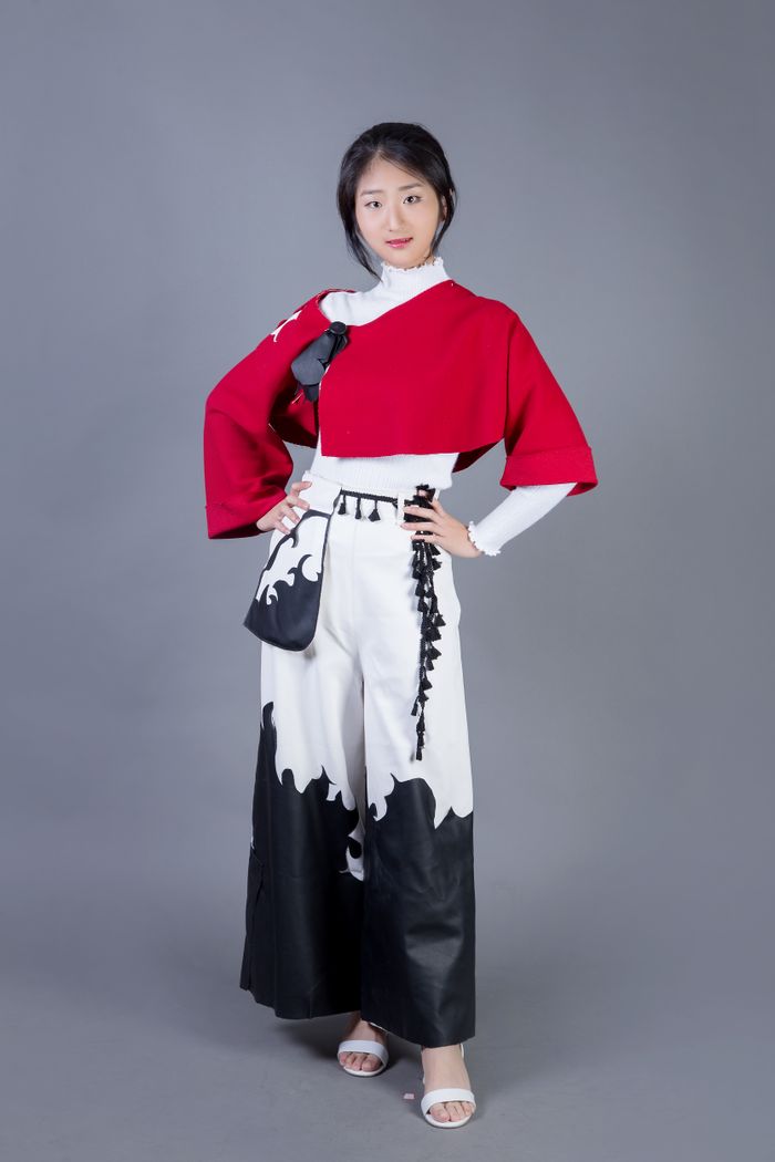 Fashion-forward woman in a striking red and white outfit posing confidently in a studio setting.