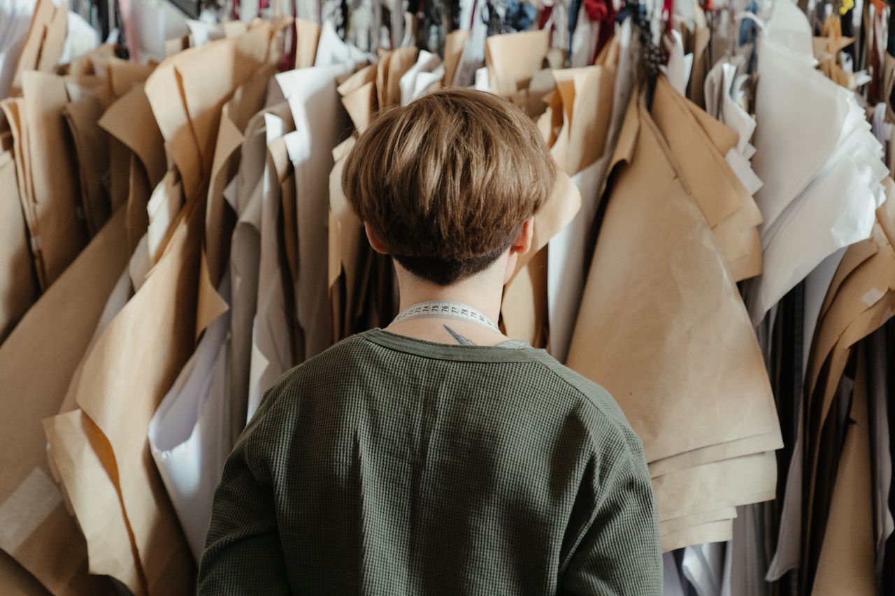 Mastering the First Impression: Your intriguing post title goes here Back view of a fashion designer surrounded by craft paper and sewing patterns in a studio setting.
